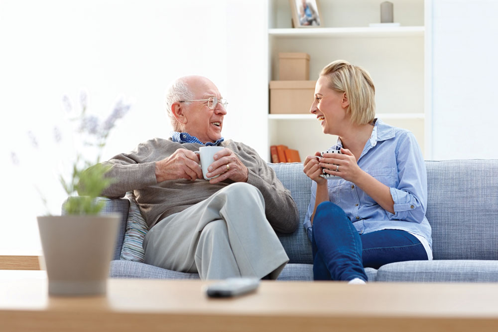 Personal Care Resident sitting with daughter drinking coffee on couch